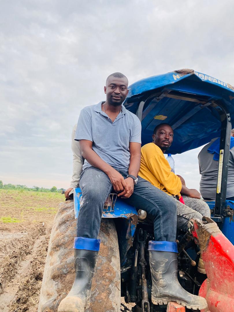 Two men sitting on a tractor at the edge of a freshly ploughed field.
